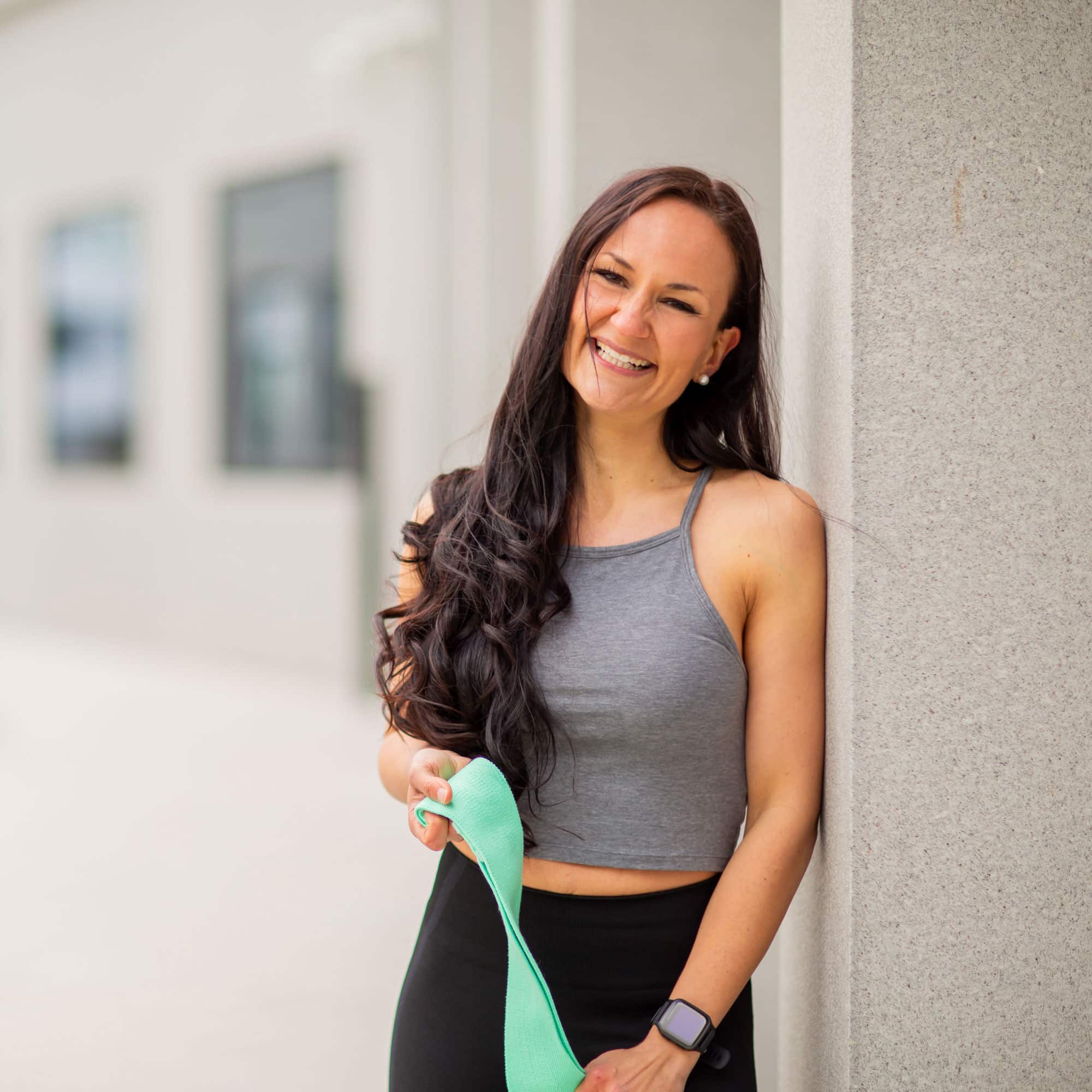 Elena holding a band and smiling while leaning against the wall