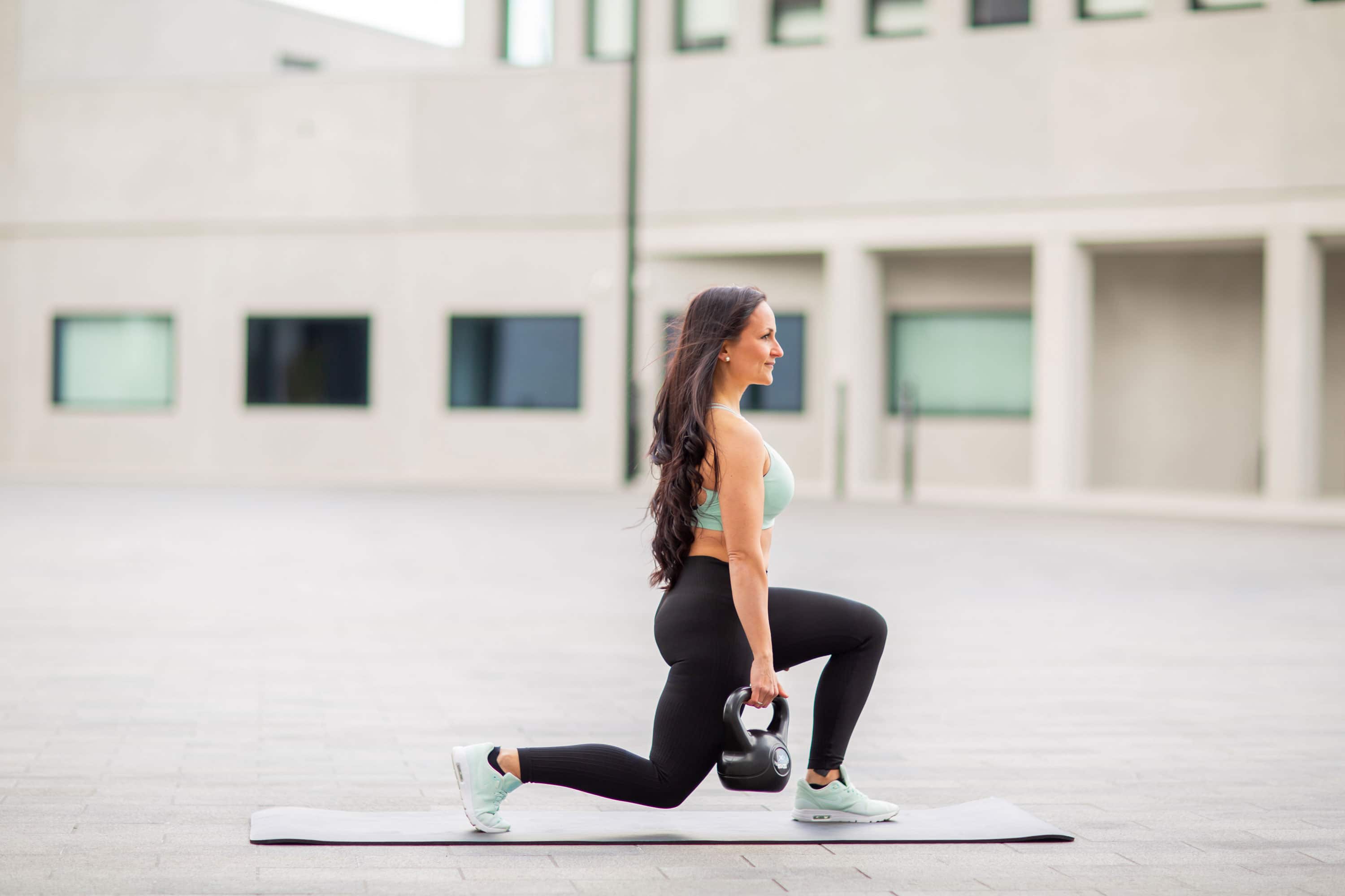 Elena doing a lunge exercise on a mat outside